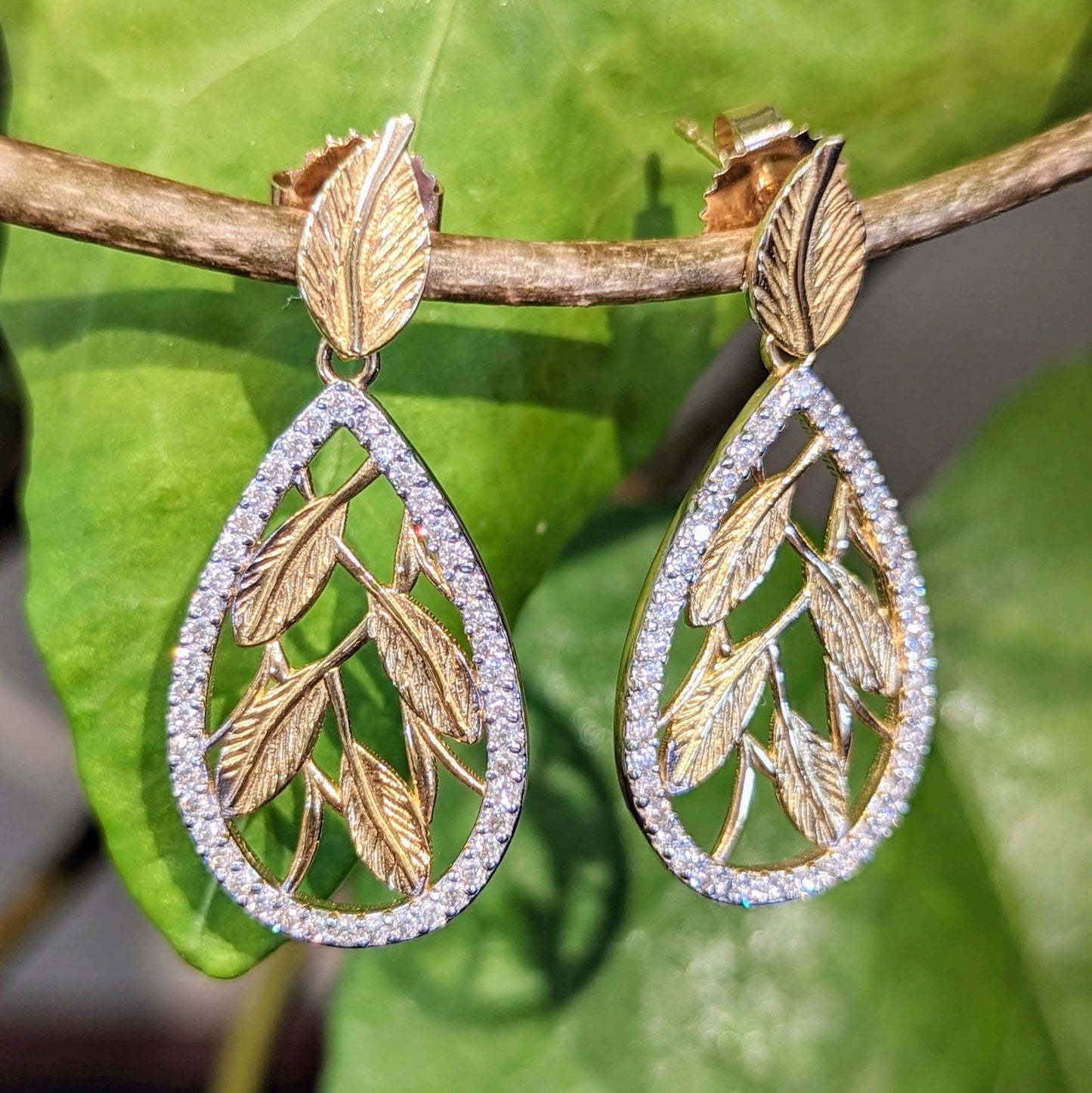Photo of Etched leaf diamond earrings in a decorative scene, designed by , available at Plumb Gold & Plumb Silver