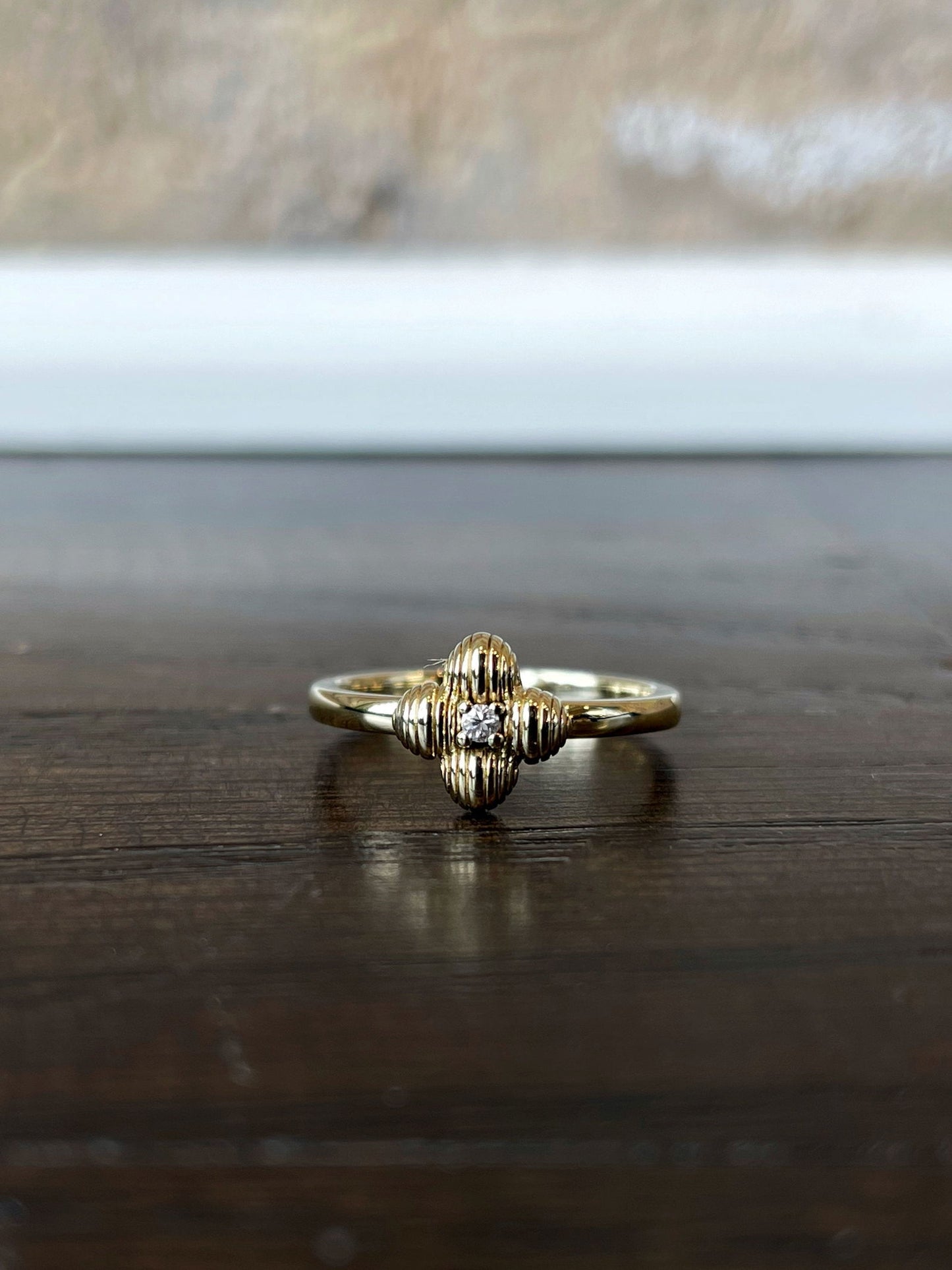Photo of Four Leaf Ring in a decorative scene, designed by , available at Plumb Gold & Plumb Silver