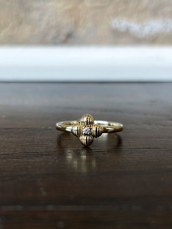 Photo of Four Leaf Ring in a decorative scene, designed by , available at Plumb Gold & Plumb Silver