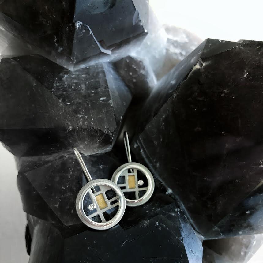 Photo of Geometric Circle Earrings with Diamond Accents in a decorative scene, designed by , available at Plumb Gold & Plumb Silver