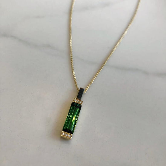 Photo of Green Tourmaline and Diamond Bar Pendant in a decorative scene, designed by , available at Plumb Gold & Plumb Silver
