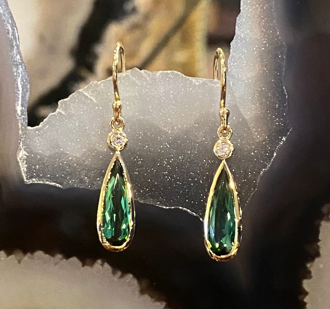 Photo of Green Tourmaline and Diamond Drop Earrings in a decorative scene, designed by , available at Plumb Gold & Plumb Silver