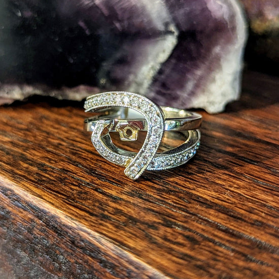Photo of H L Swirl Bypass Ring Mounting in a decorative scene, designed by , available at Plumb Gold & Plumb Silver