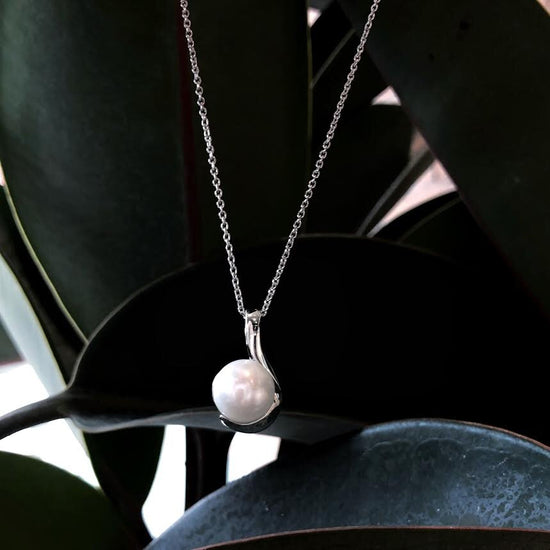 Photo of Half Swirl Pearl Pendant in a decorative scene, designed by , available at Plumb Gold & Plumb Silver