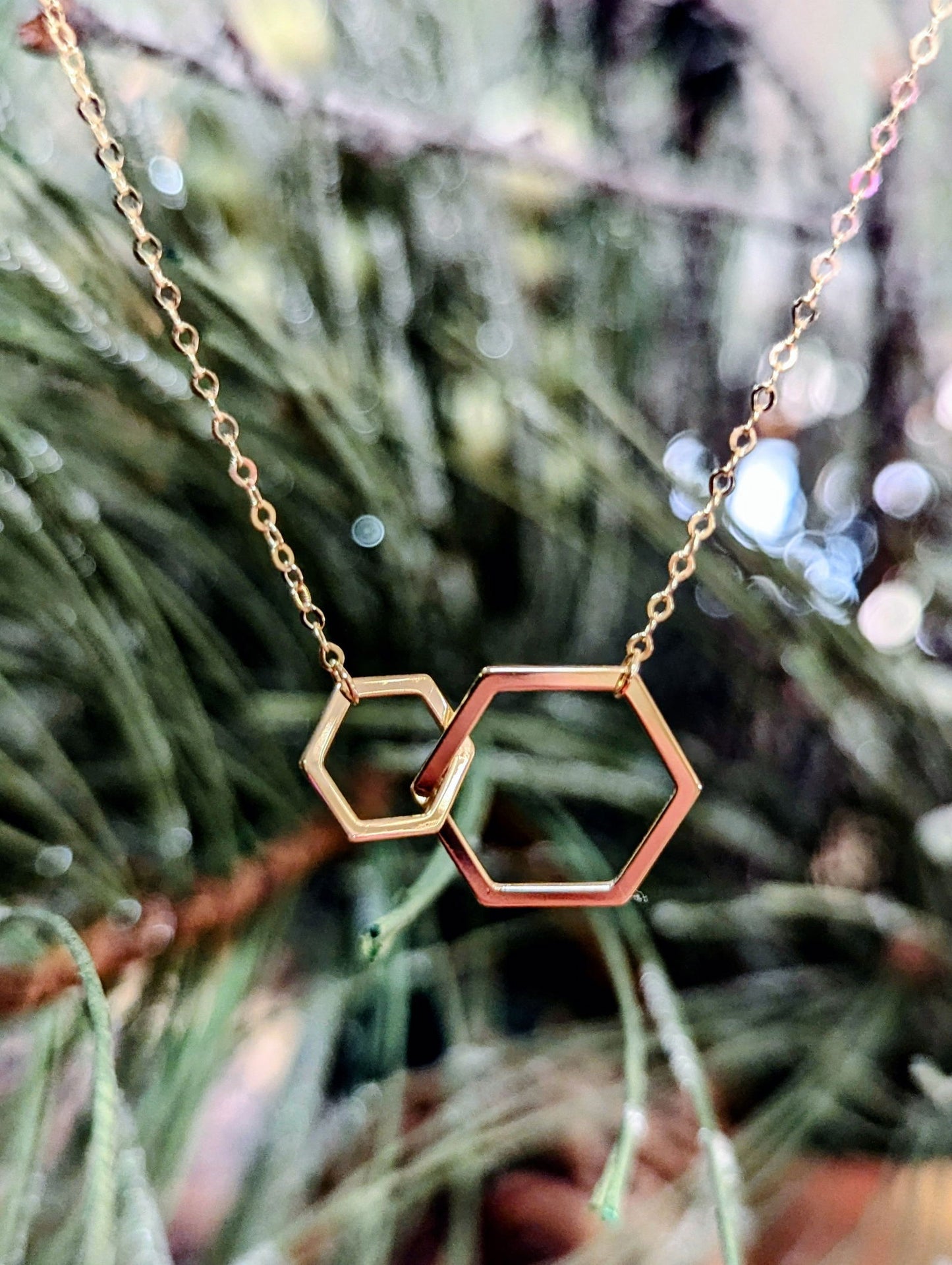 Photo of Hexagon necklace in a decorative scene, designed by , available at Plumb Gold & Plumb Silver