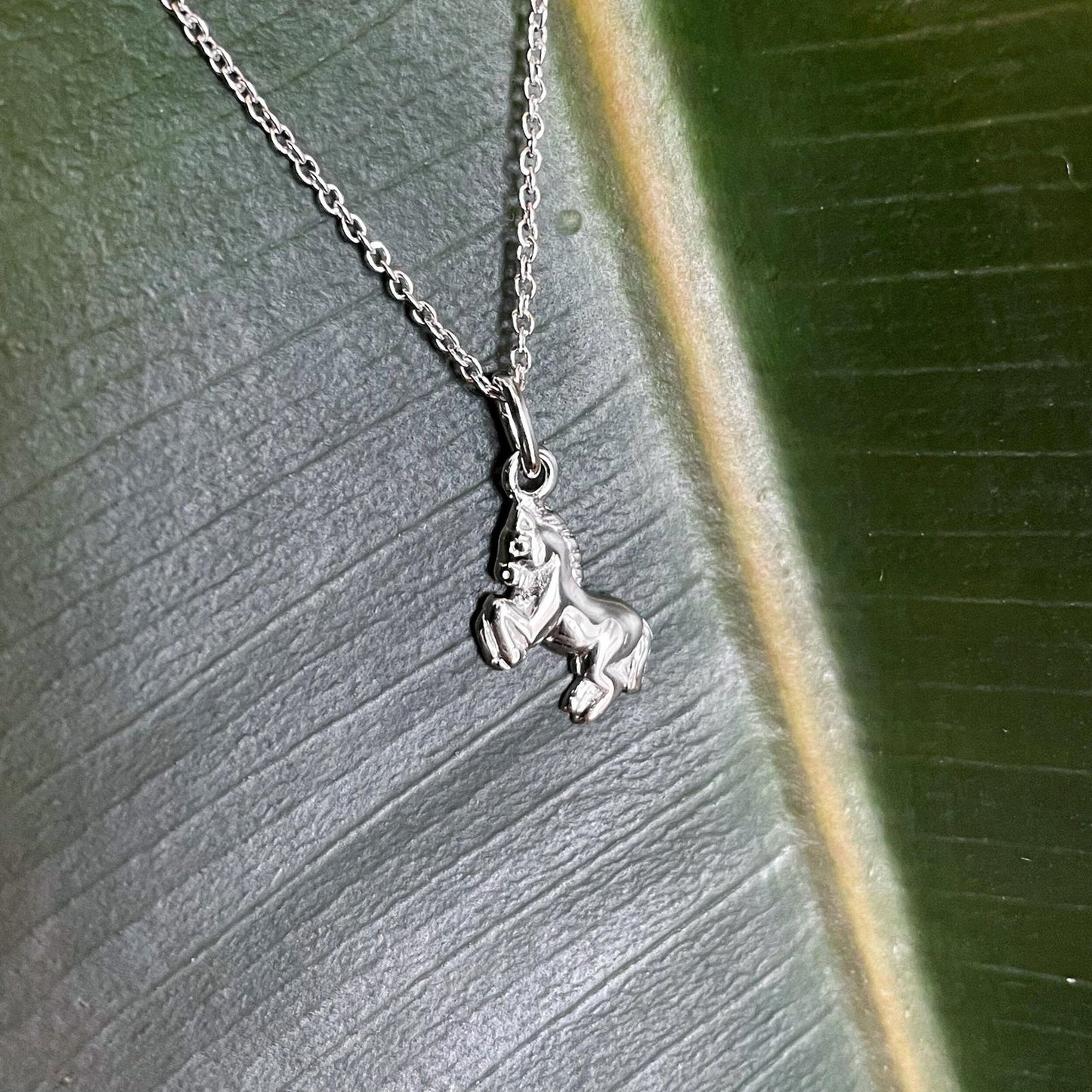 Photo of Horse Necklace in a decorative scene, designed by , available at Plumb Gold & Plumb Silver