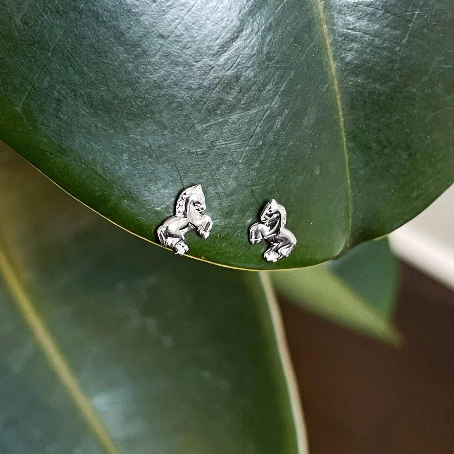 Photo of Horse Stud Earrings in a decorative scene, designed by , available at Plumb Gold & Plumb Silver