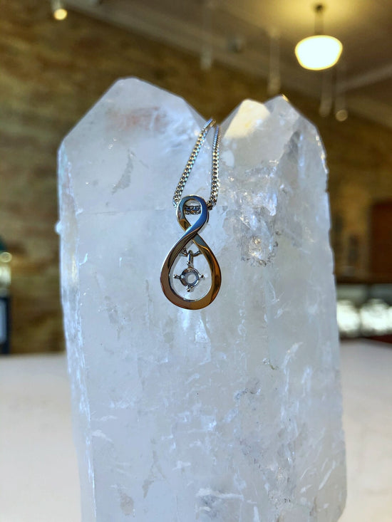 Photo of Infinity with Dangle in a decorative scene, designed by , available at Plumb Gold & Plumb Silver