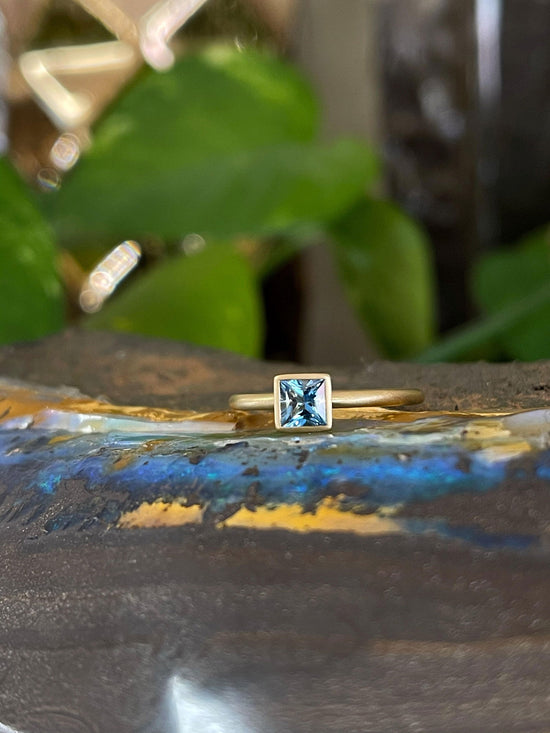 Photo of Kim Collins Aquamarine Yum Drop in a decorative scene, designed by , available at Plumb Gold & Plumb Silver