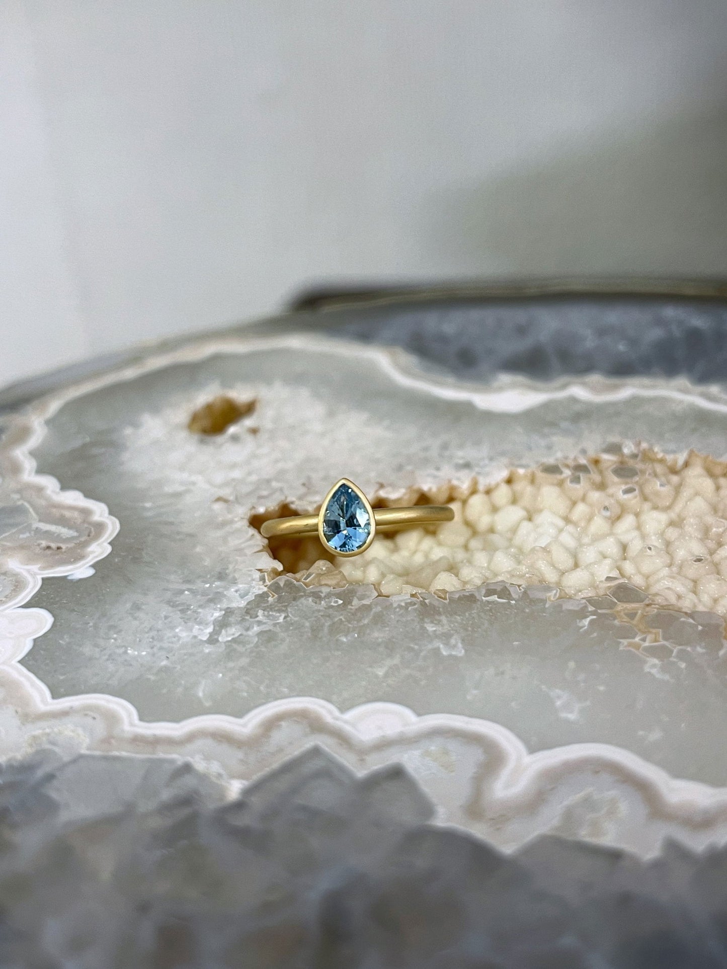 Photo of Kim Collins Aquamarine Yumdrop in a decorative scene, designed by , available at Plumb Gold & Plumb Silver