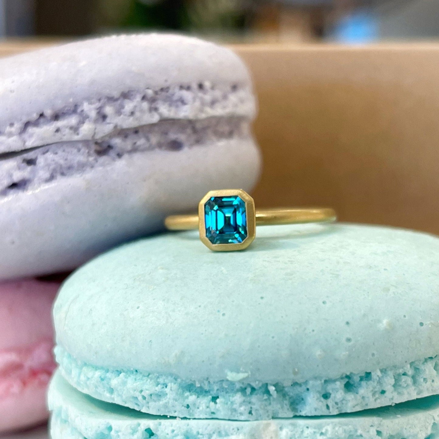 Photo of Kim Collins Blue Zircon Yumdrop Ring in a decorative scene, designed by , available at Plumb Gold & Plumb Silver