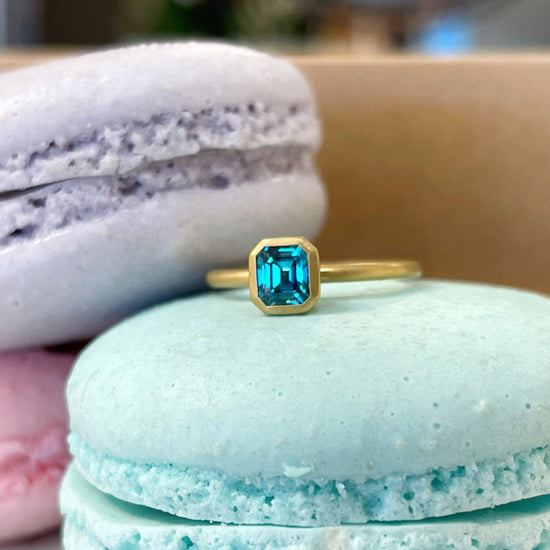 Photo of Kim Collins Blue Zircon Yumdrop Ring in a decorative scene, designed by , available at Plumb Gold & Plumb Silver