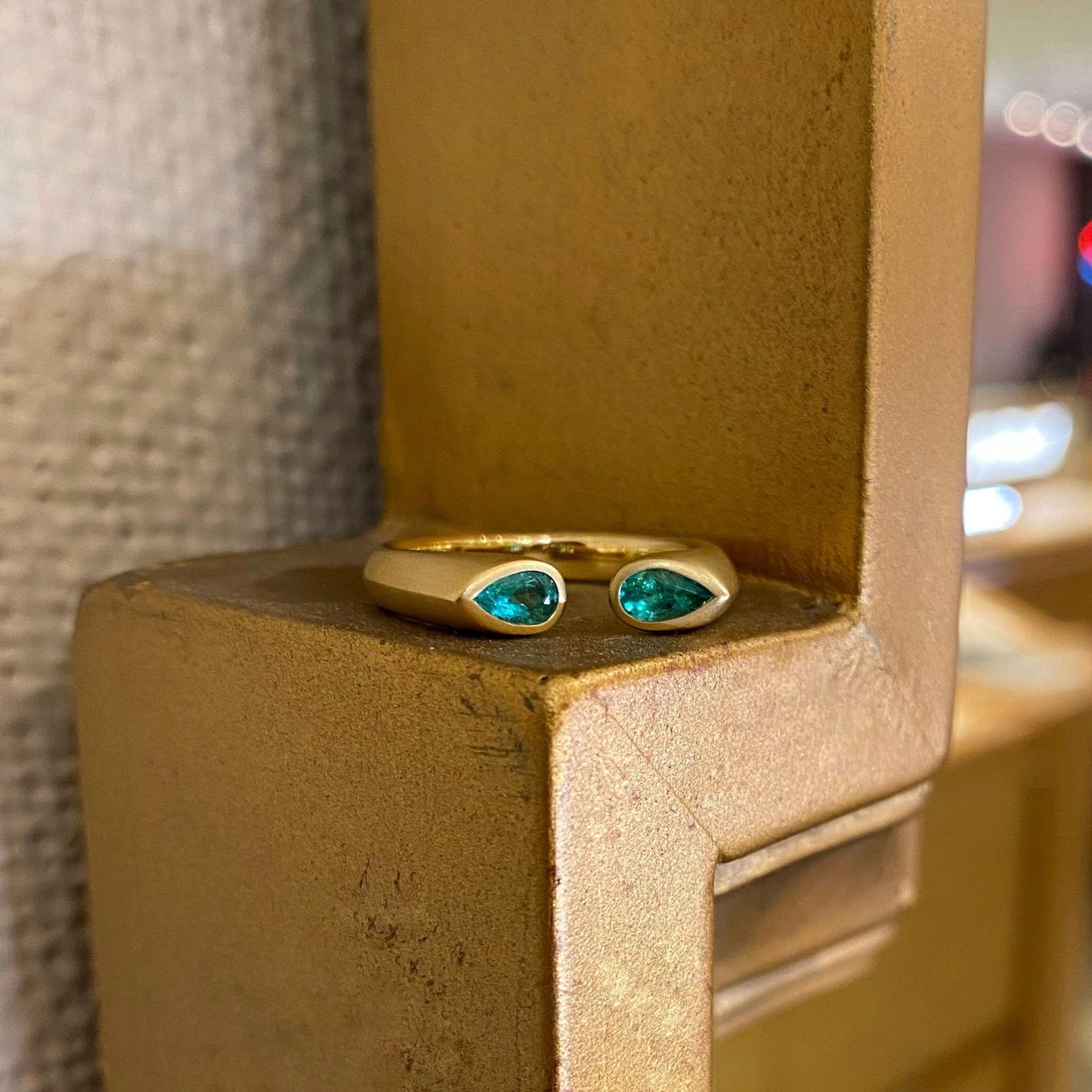 Photo of Kim Collins Emerald "Embrace" Ring in a decorative scene, designed by , available at Plumb Gold & Plumb Silver