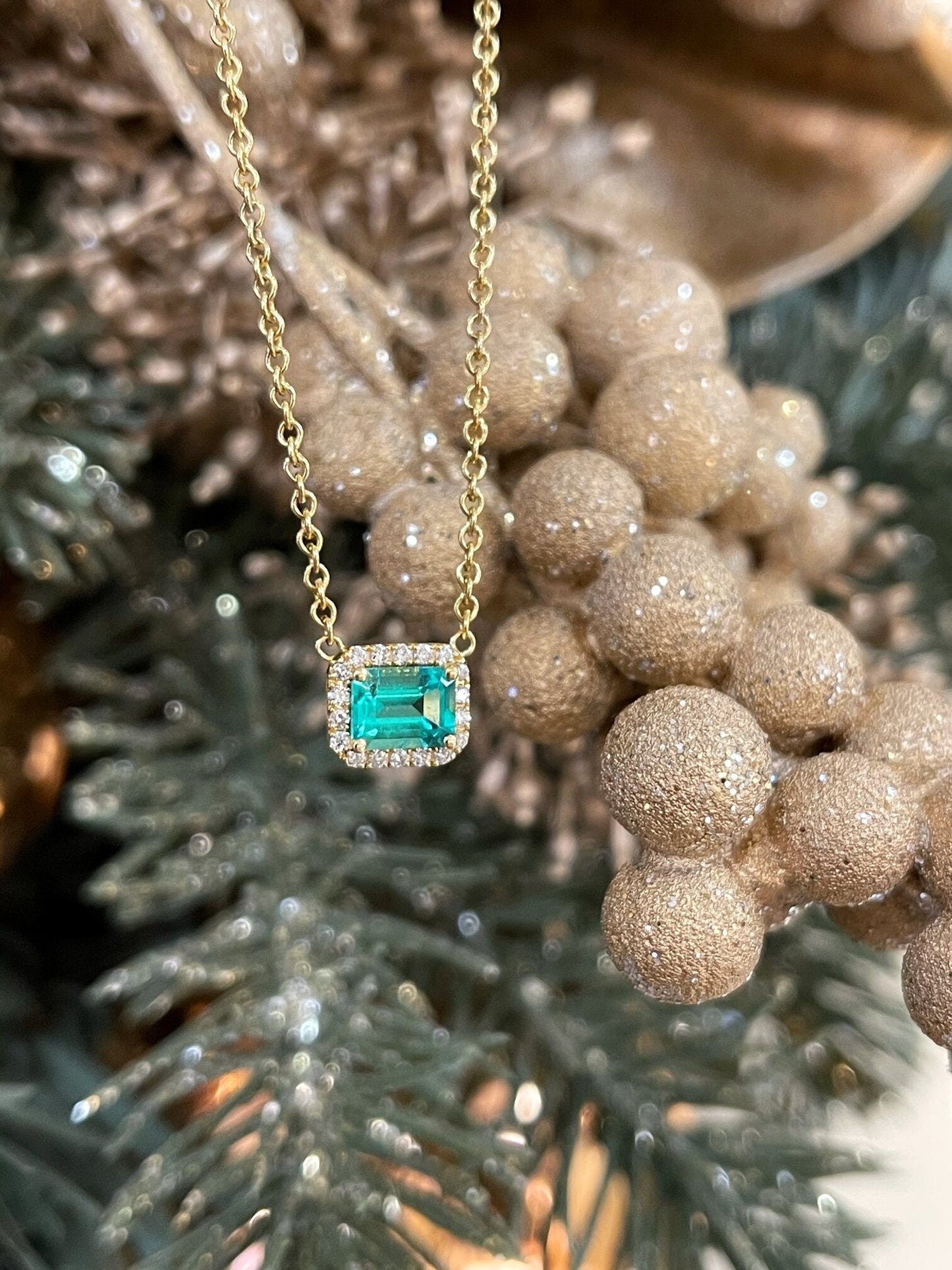Photo of Kim Collins Emerald and Diamond Necklace in a decorative scene, designed by , available at Plumb Gold & Plumb Silver