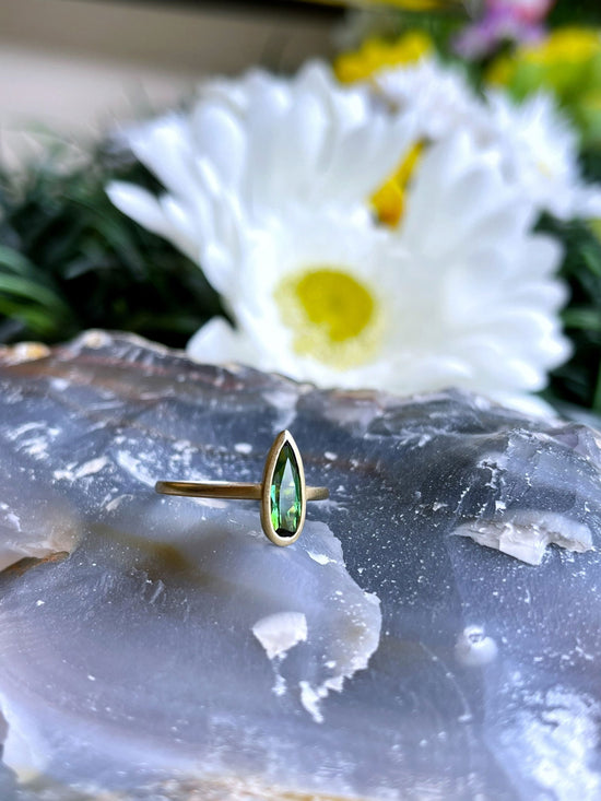 Photo of Kim Collins Green Tourmaline Yumdrop in a decorative scene, designed by , available at Plumb Gold & Plumb Silver