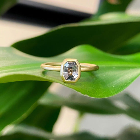 Photo of Kim Collins Grey Spinel Yum Drop Ring in a decorative scene, designed by , available at Plumb Gold & Plumb Silver