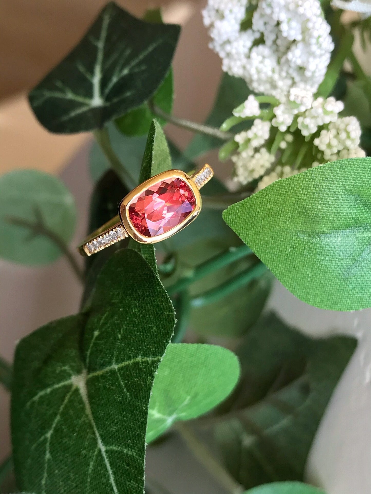 Photo of Kim Collins Peach Spinel Ring in a decorative scene, designed by , available at Plumb Gold & Plumb Silver