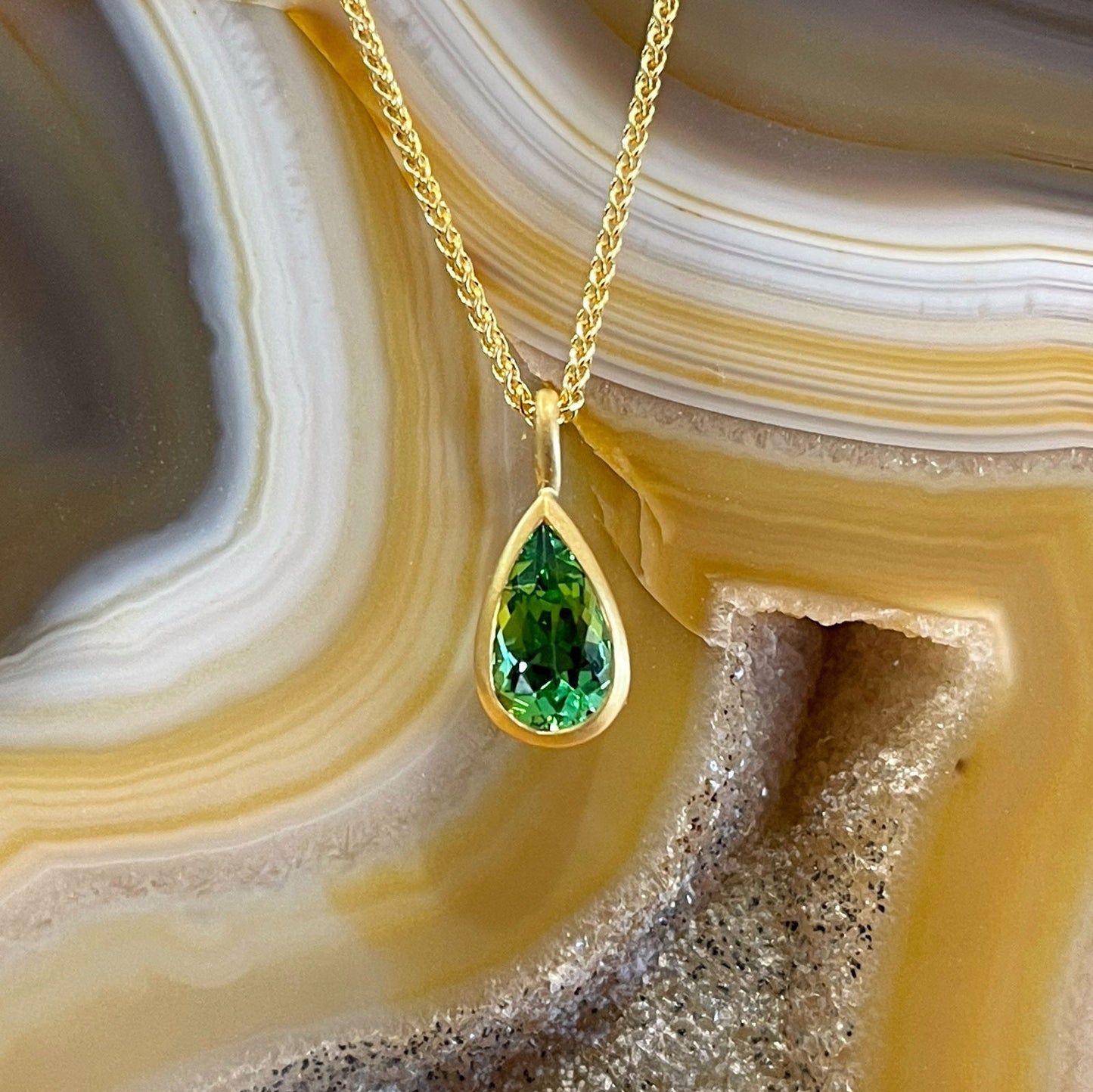 Photo of Kimberly Collins Green Tourmaline Pendant in a decorative scene, designed by , available at Plumb Gold & Plumb Silver