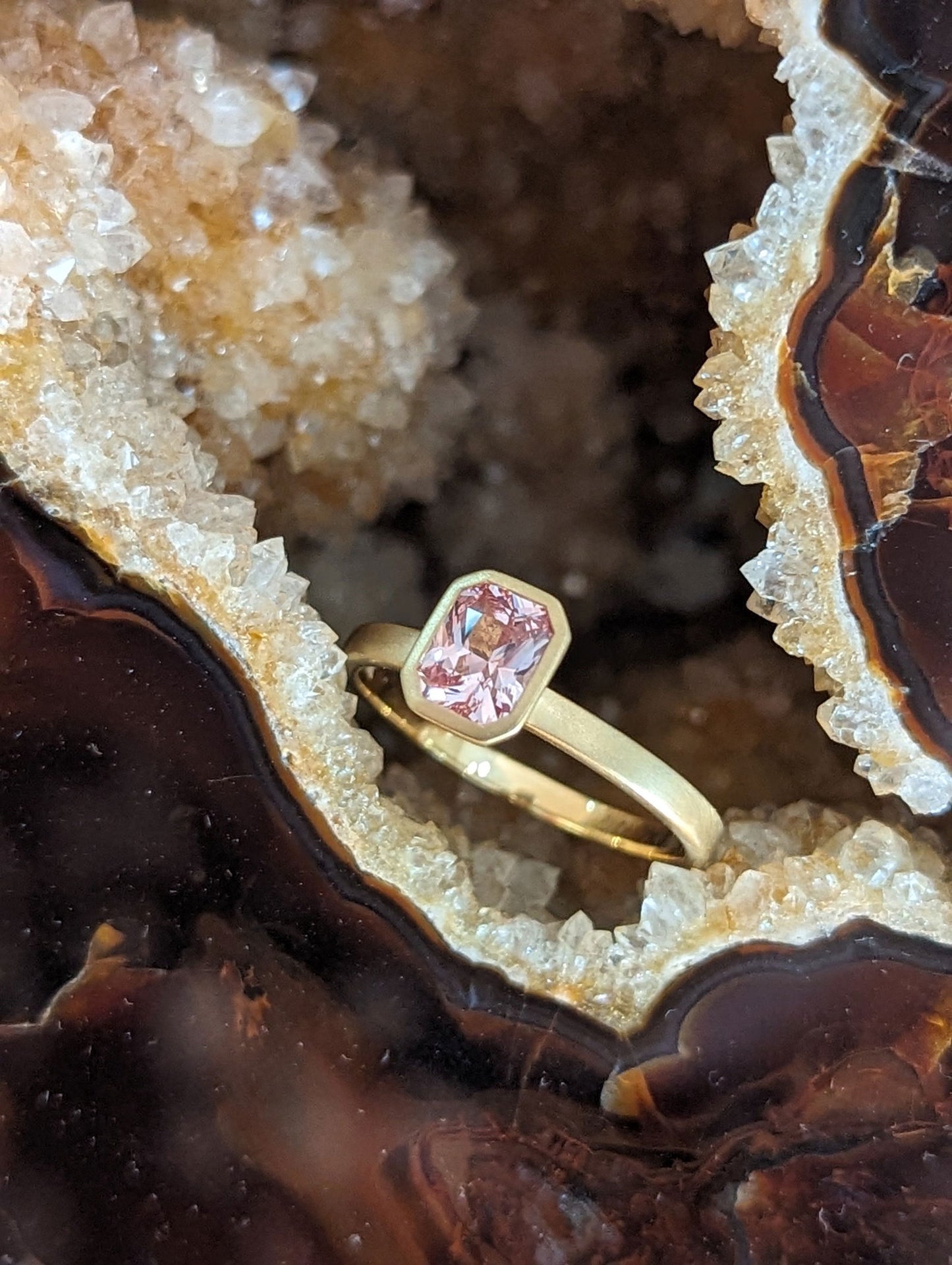 Photo of Kimberly Collins Peach Sapphire Yum Drop Ring in a decorative scene, designed by , available at Plumb Gold & Plumb Silver