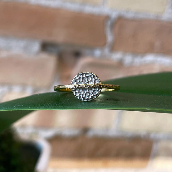 Photo of “Kymbal” Ring in a decorative scene, designed by , available at Plumb Gold & Plumb Silver