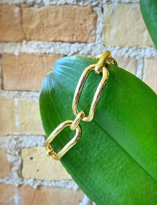 Photo of Large Paper Clip Link Bracelet in a decorative scene, designed by , available at Plumb Gold & Plumb Silver