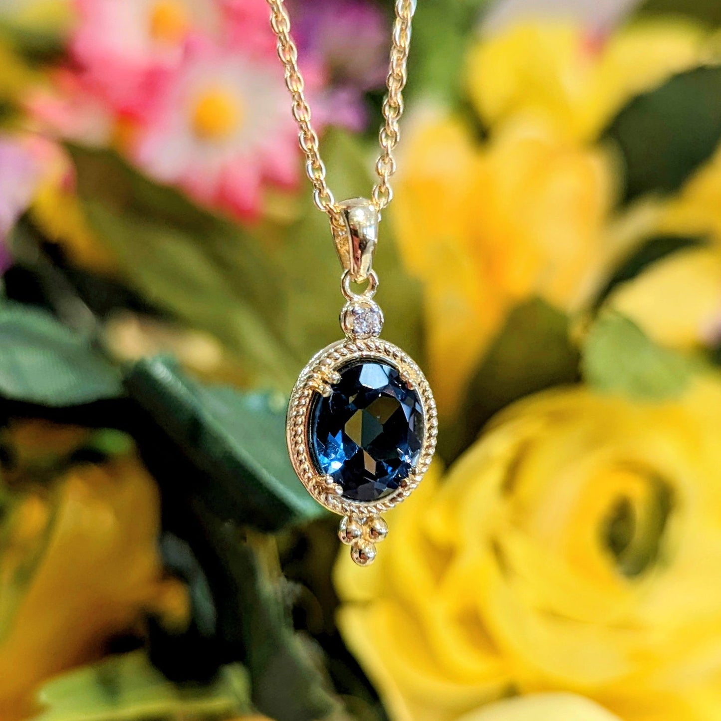 Photo of London Blue Topaz Beaded Pendant in a decorative scene, designed by , available at Plumb Gold & Plumb Silver