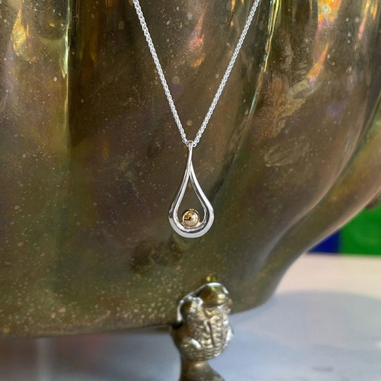 Photo of "Mana" Necklace in a decorative scene, designed by , available at Plumb Gold & Plumb Silver