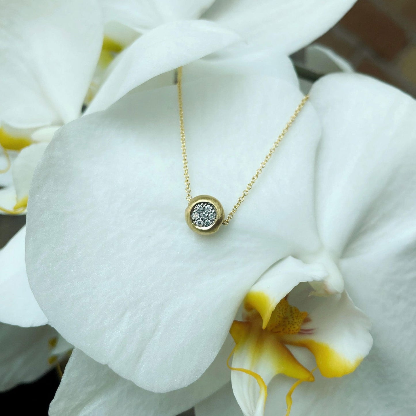 Photo of Matte Pavé Diamond Slide Necklace in a decorative scene, designed by , available at Plumb Gold & Plumb Silver