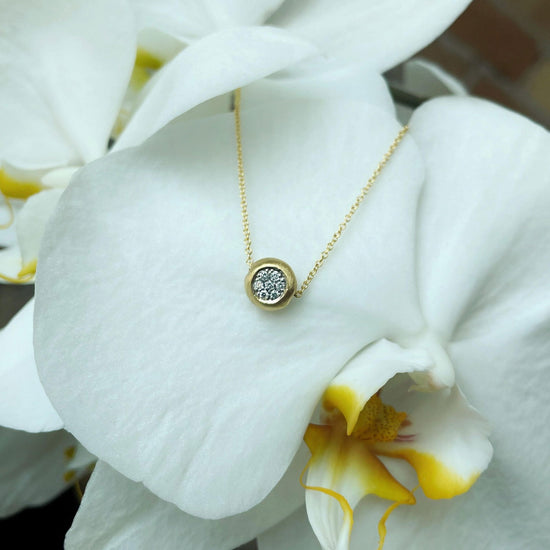Photo of Matte Pavé Diamond Slide Necklace in a decorative scene, designed by , available at Plumb Gold & Plumb Silver