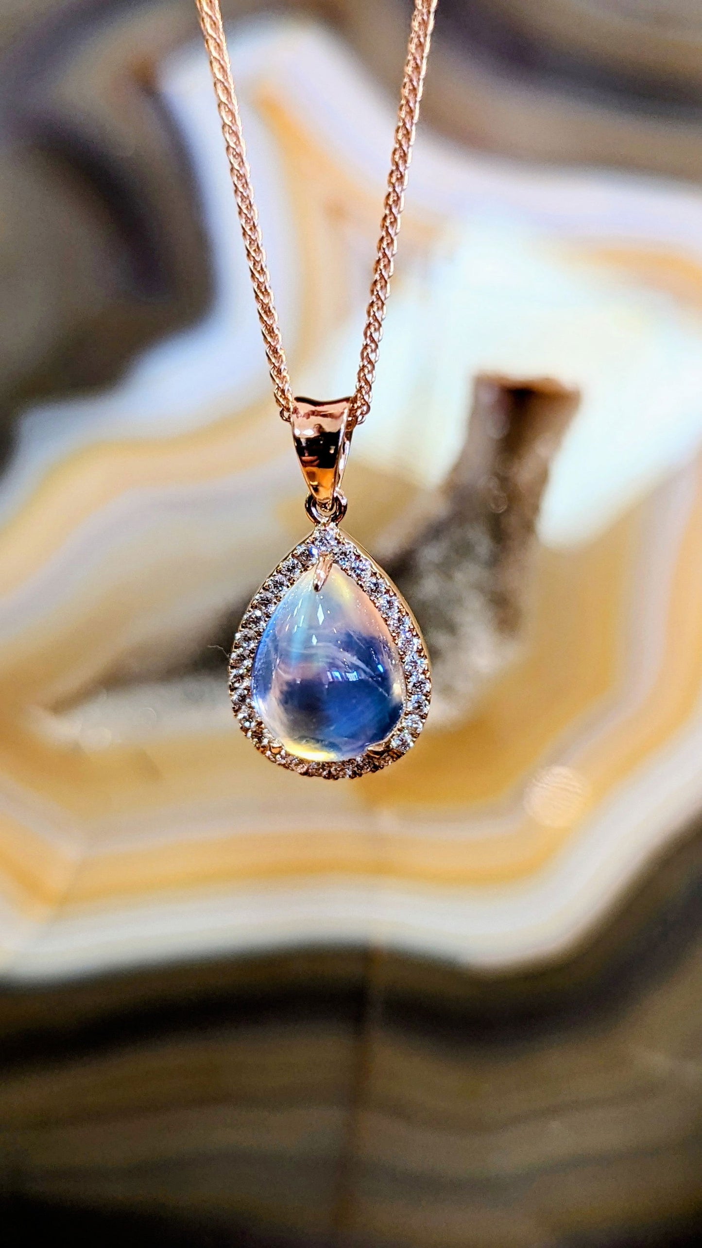 Photo of Moonstone Halo Pendant in a decorative scene, designed by , available at Plumb Gold & Plumb Silver