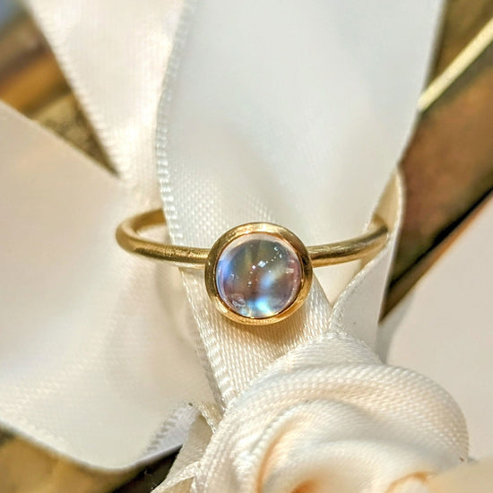 Photo of Moonstone Yumdrop Ring in a decorative scene, designed by , available at Plumb Gold & Plumb Silver