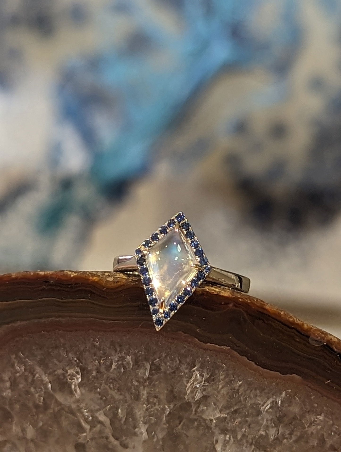 Photo of Moonstone and Sapphire Ring in a decorative scene, designed by , available at Plumb Gold & Plumb Silver