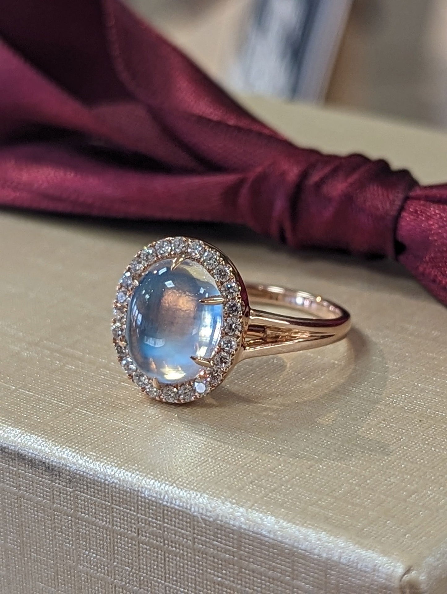 Photo of Moonstone halo Ring in a decorative scene, designed by , available at Plumb Gold & Plumb Silver