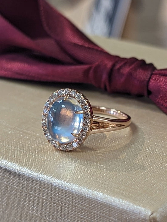 Photo of Moonstone halo Ring in a decorative scene, designed by , available at Plumb Gold & Plumb Silver