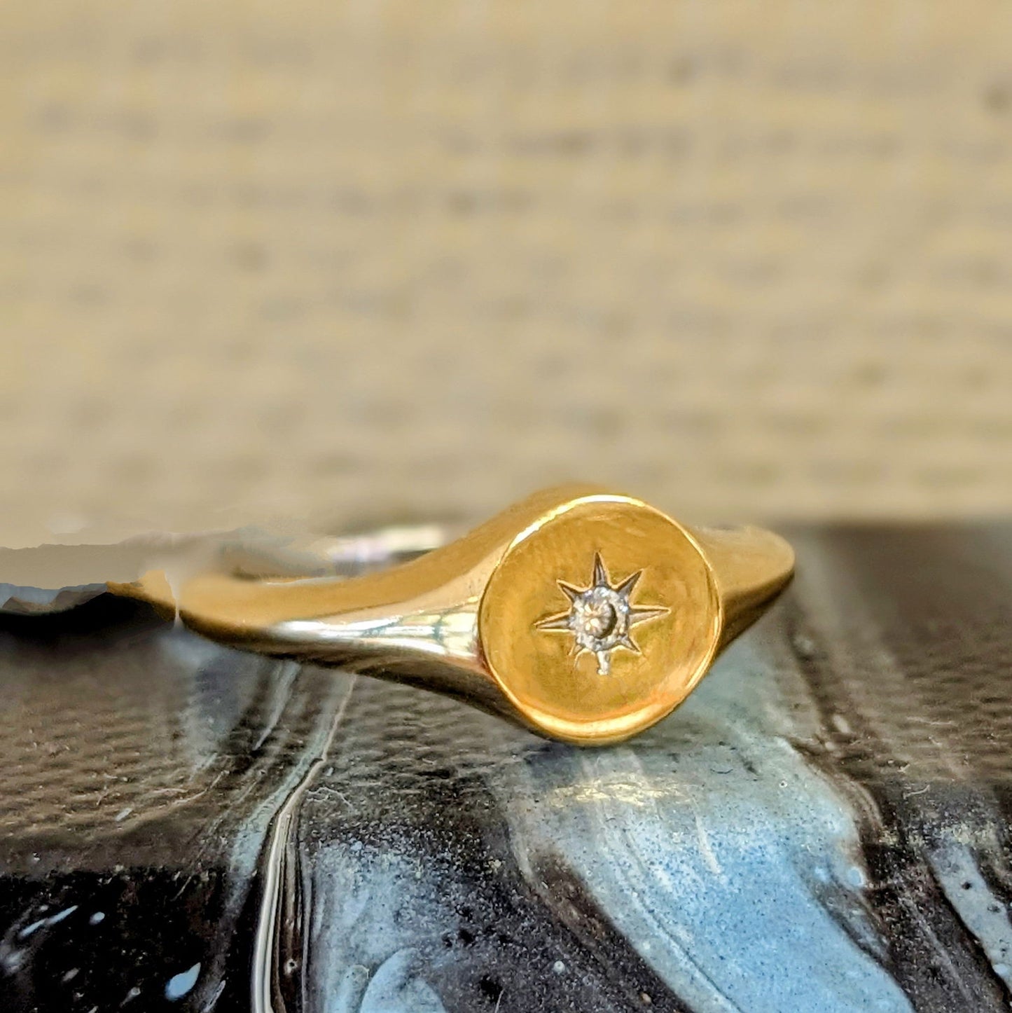 Photo of Nautical Star Signet Ring in a decorative scene, designed by , available at Plumb Gold & Plumb Silver