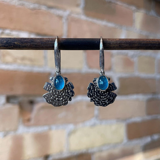 Photo of “Oak” Apatite Dangles in a decorative scene, designed by , available at Plumb Gold & Plumb Silver
