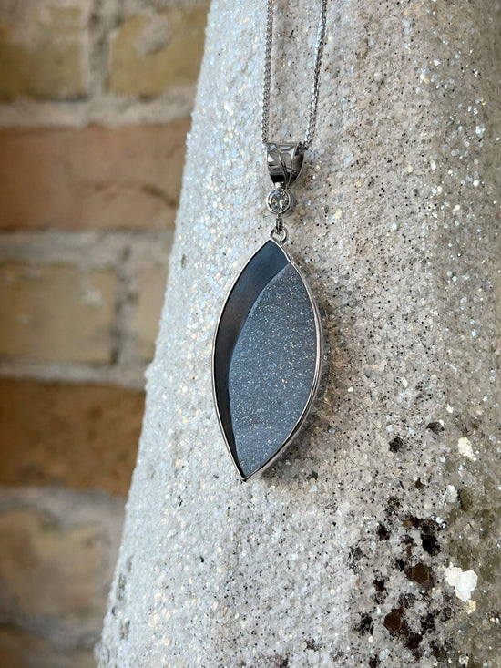 Photo of Onyx and Druzy Pendant in a decorative scene, designed by , available at Plumb Gold & Plumb Silver