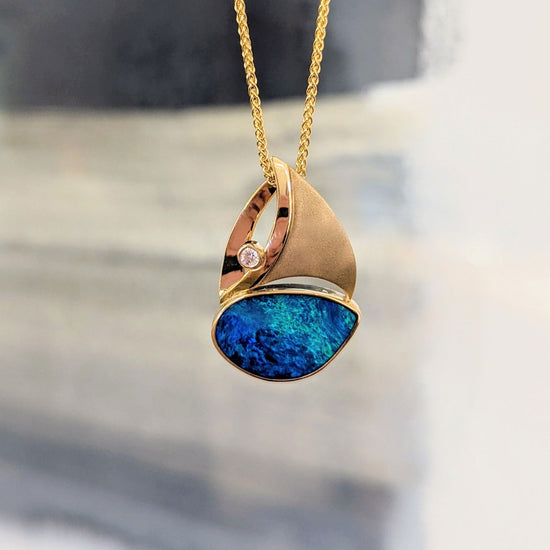 Photo of Opal Sailboat Pendant in a decorative scene, designed by , available at Plumb Gold & Plumb Silver