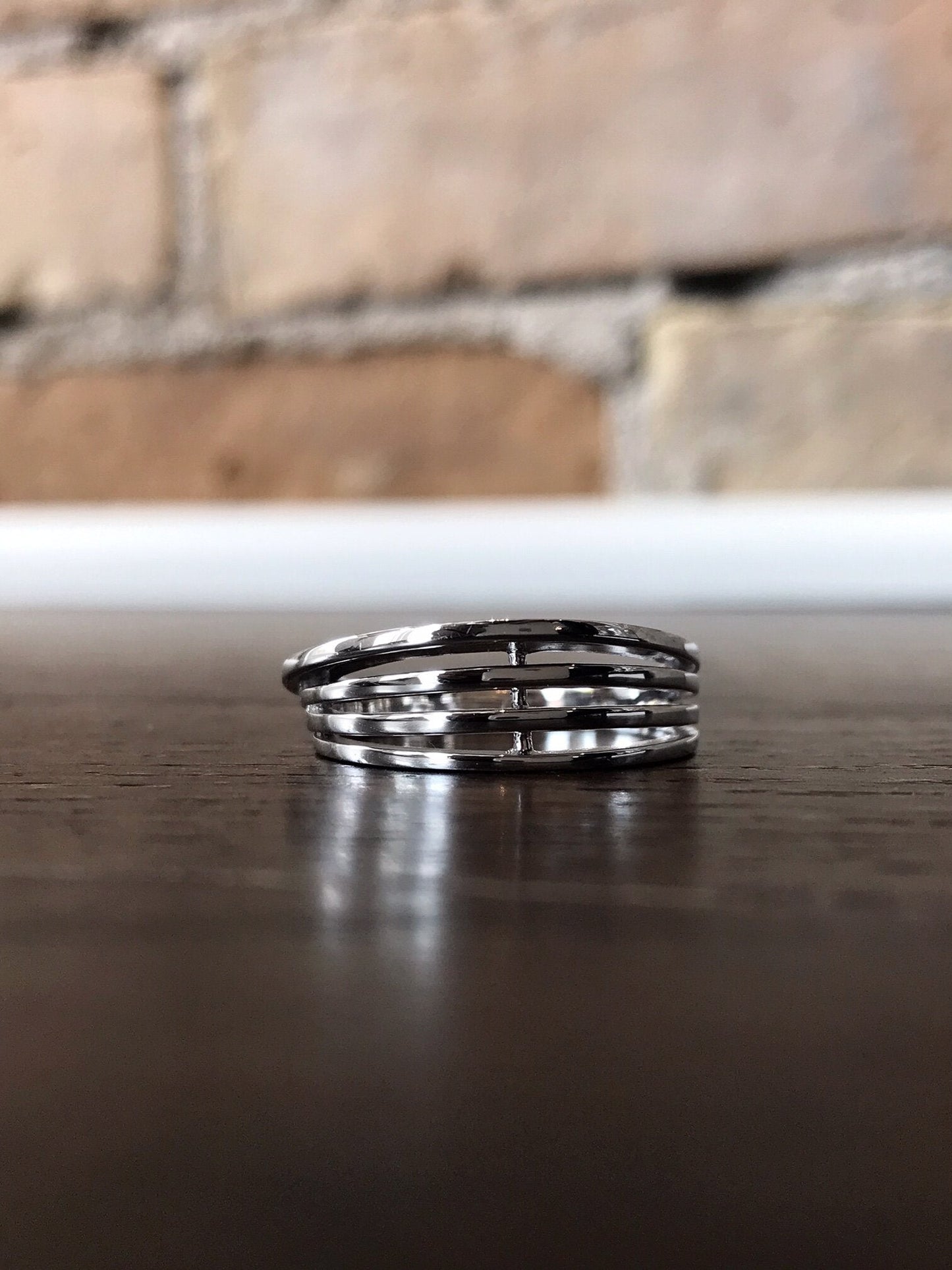 Photo of Open Four-Bar Ring in a decorative scene, designed by , available at Plumb Gold & Plumb Silver