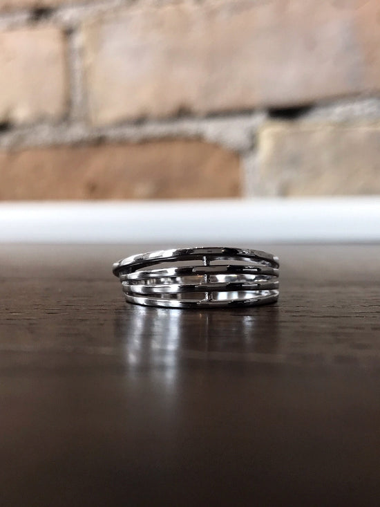 Photo of Open Four-Bar Ring in a decorative scene, designed by , available at Plumb Gold & Plumb Silver