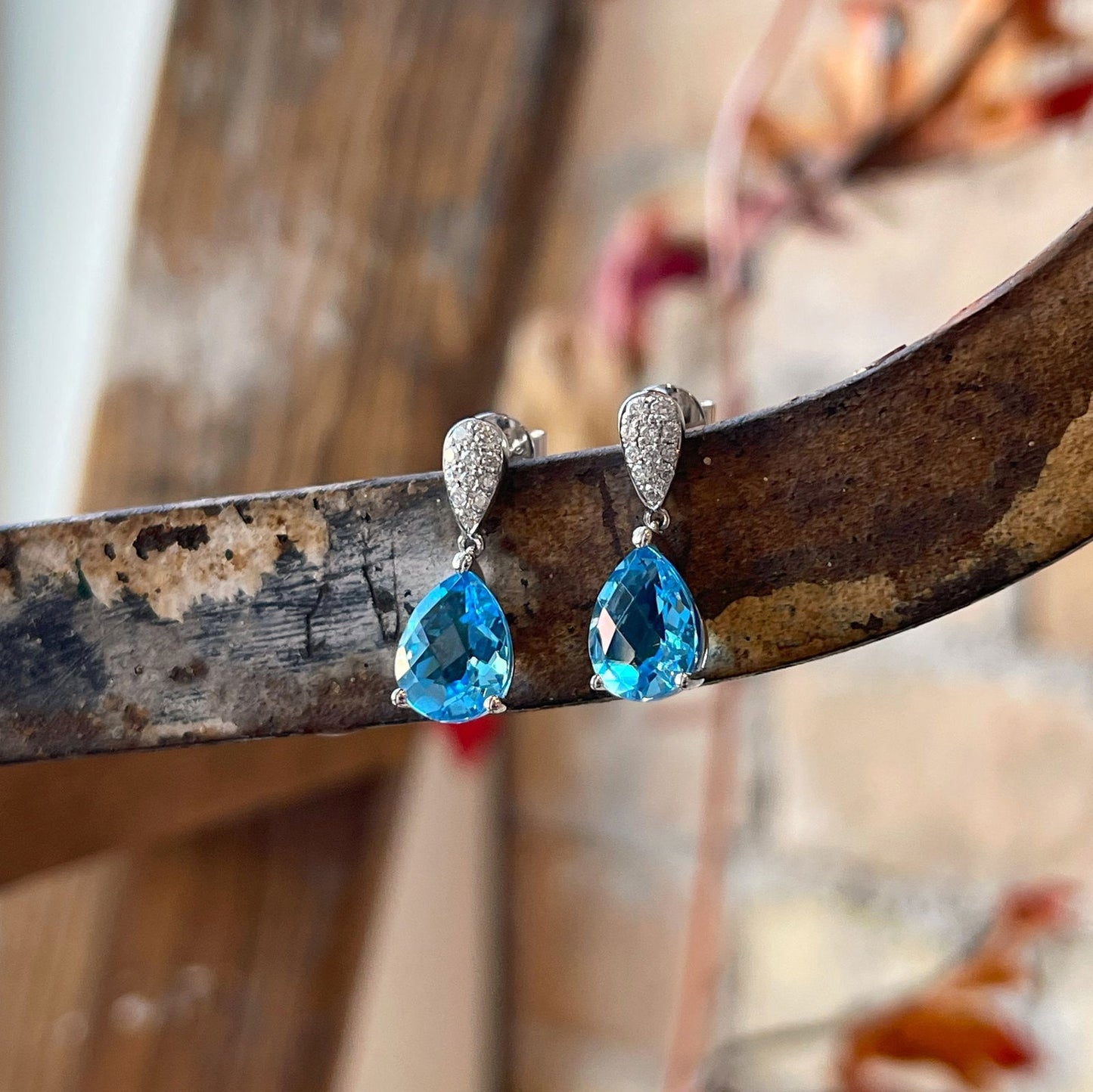 Photo of Pear Drop Blue Topaz Dangle in a decorative scene, designed by , available at Plumb Gold & Plumb Silver