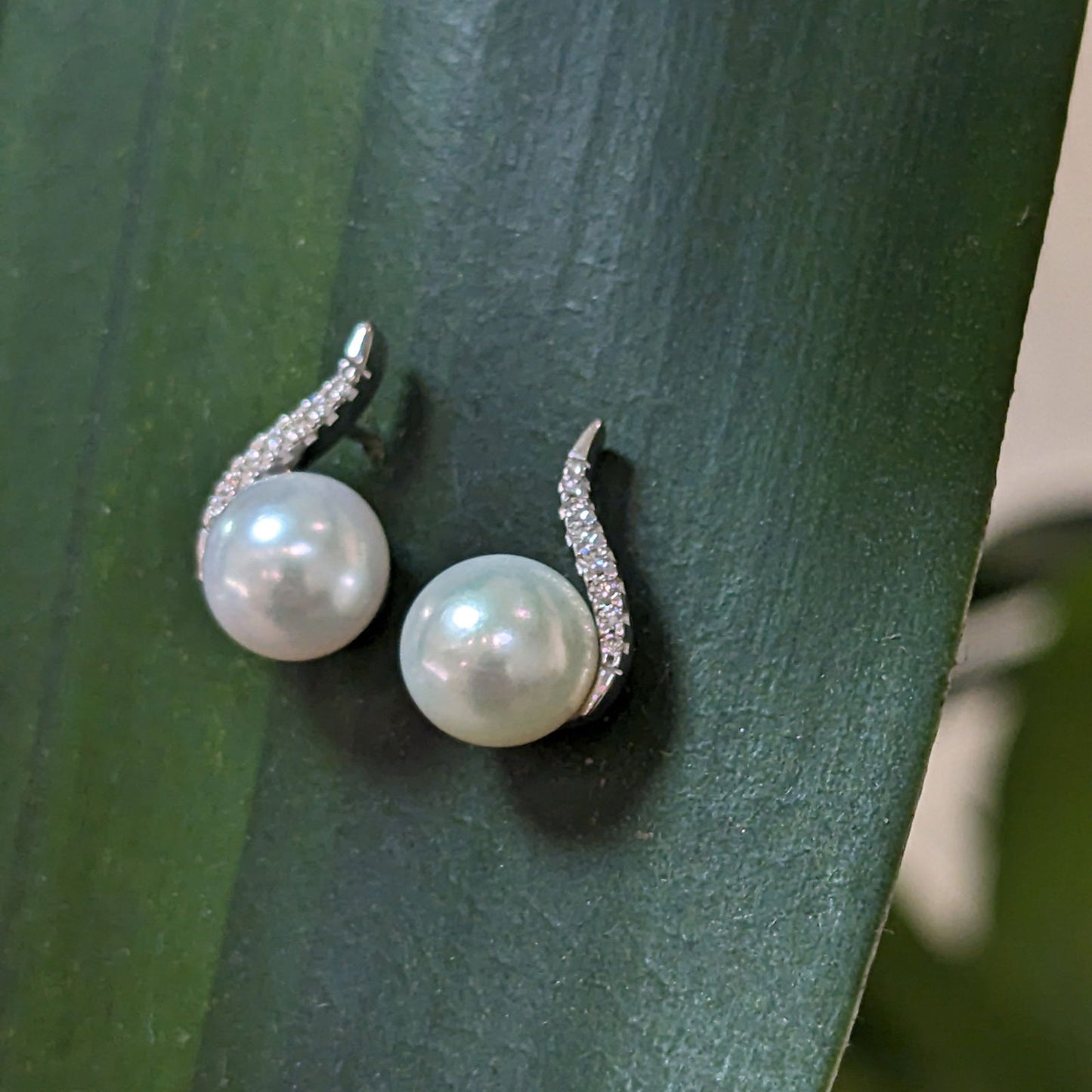 Photo of Pearl and Diamond Curve Stud in a decorative scene, designed by , available at Plumb Gold & Plumb Silver