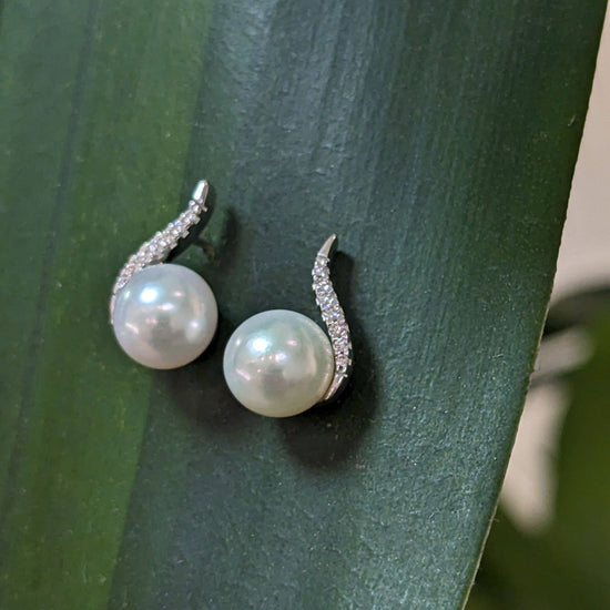 Photo of Pearl and Diamond Curve Stud in a decorative scene, designed by , available at Plumb Gold & Plumb Silver
