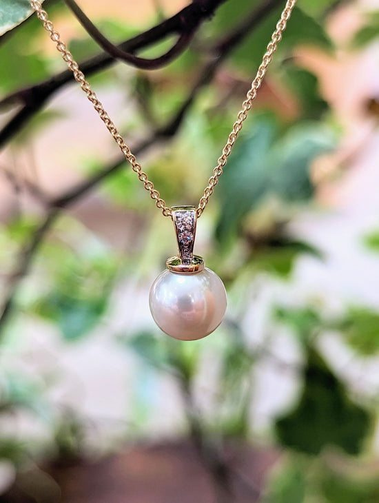 Photo of Pearl and Diamond Drop Necklace in a decorative scene, designed by , available at Plumb Gold & Plumb Silver
