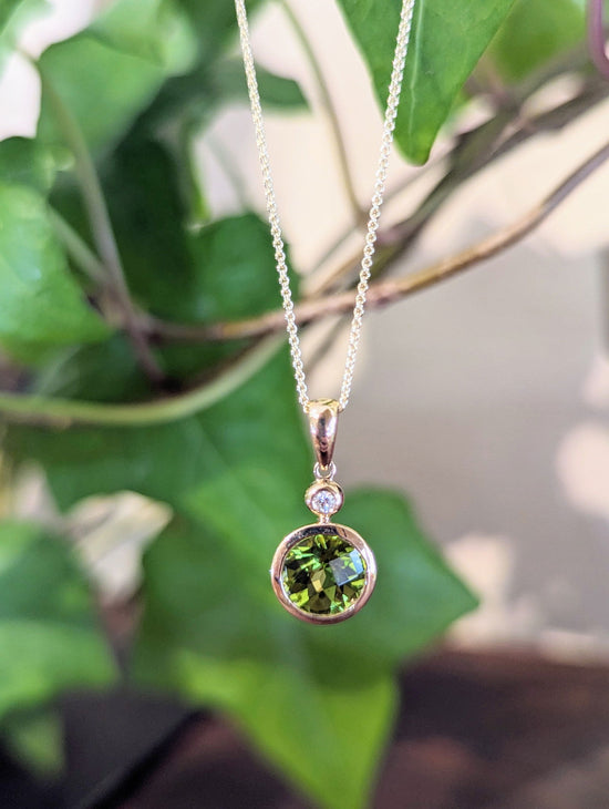 Photo of Peridot and Diamond Bezel Pendant in a decorative scene, designed by , available at Plumb Gold & Plumb Silver