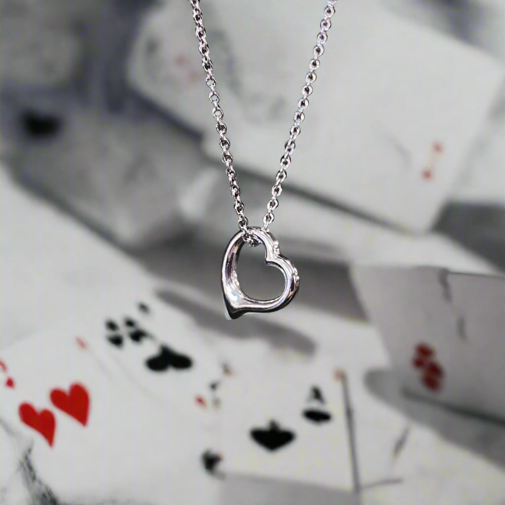 Photo of Petite Heart Necklace in a decorative scene, designed by , available at Plumb Gold & Plumb Silver