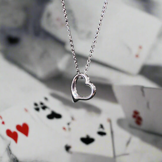 Photo of Petite Heart Necklace in a decorative scene, designed by , available at Plumb Gold & Plumb Silver