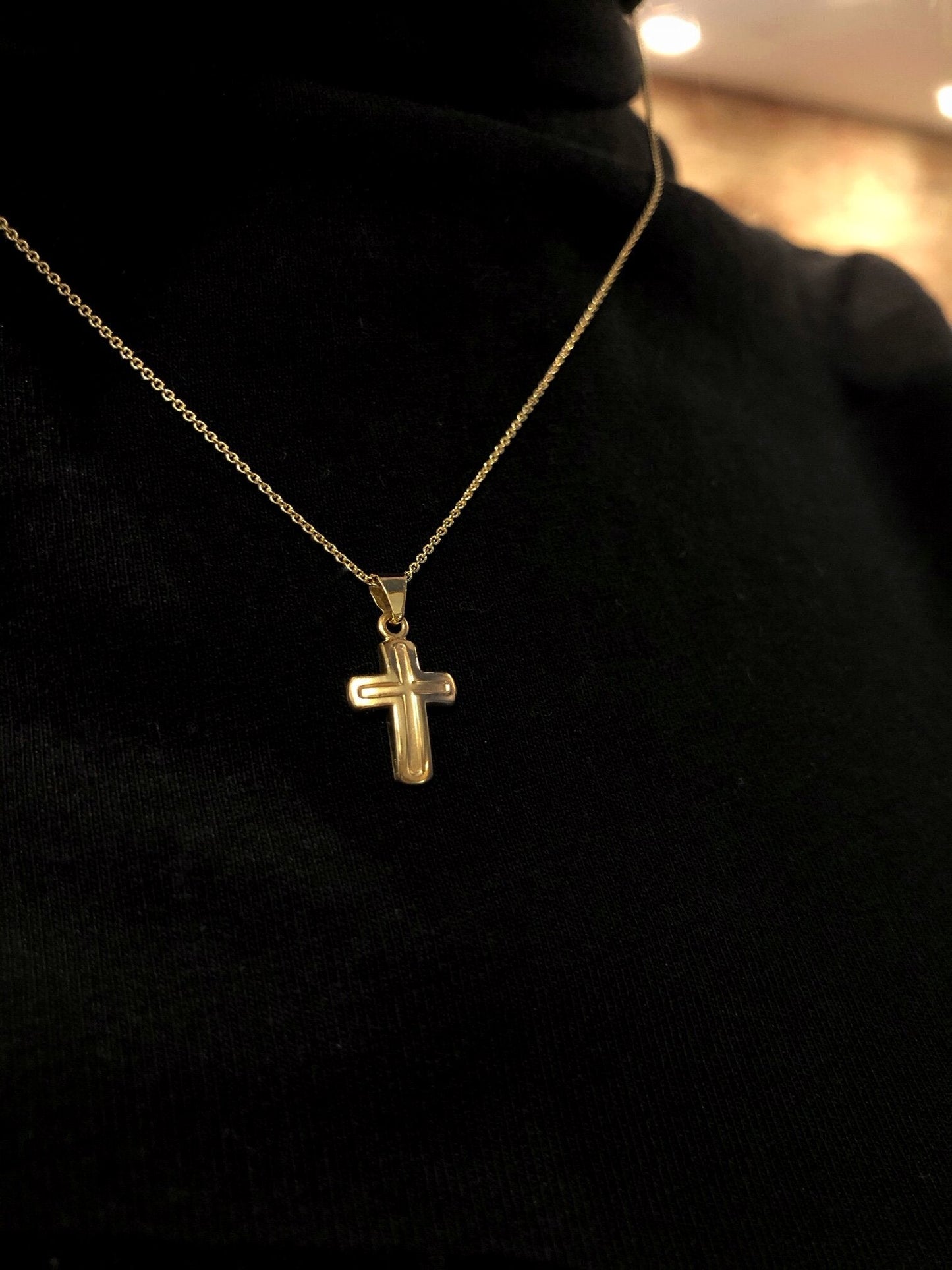 Photo of Petite Matte Cross Necklace in a decorative scene, designed by , available at Plumb Gold & Plumb Silver