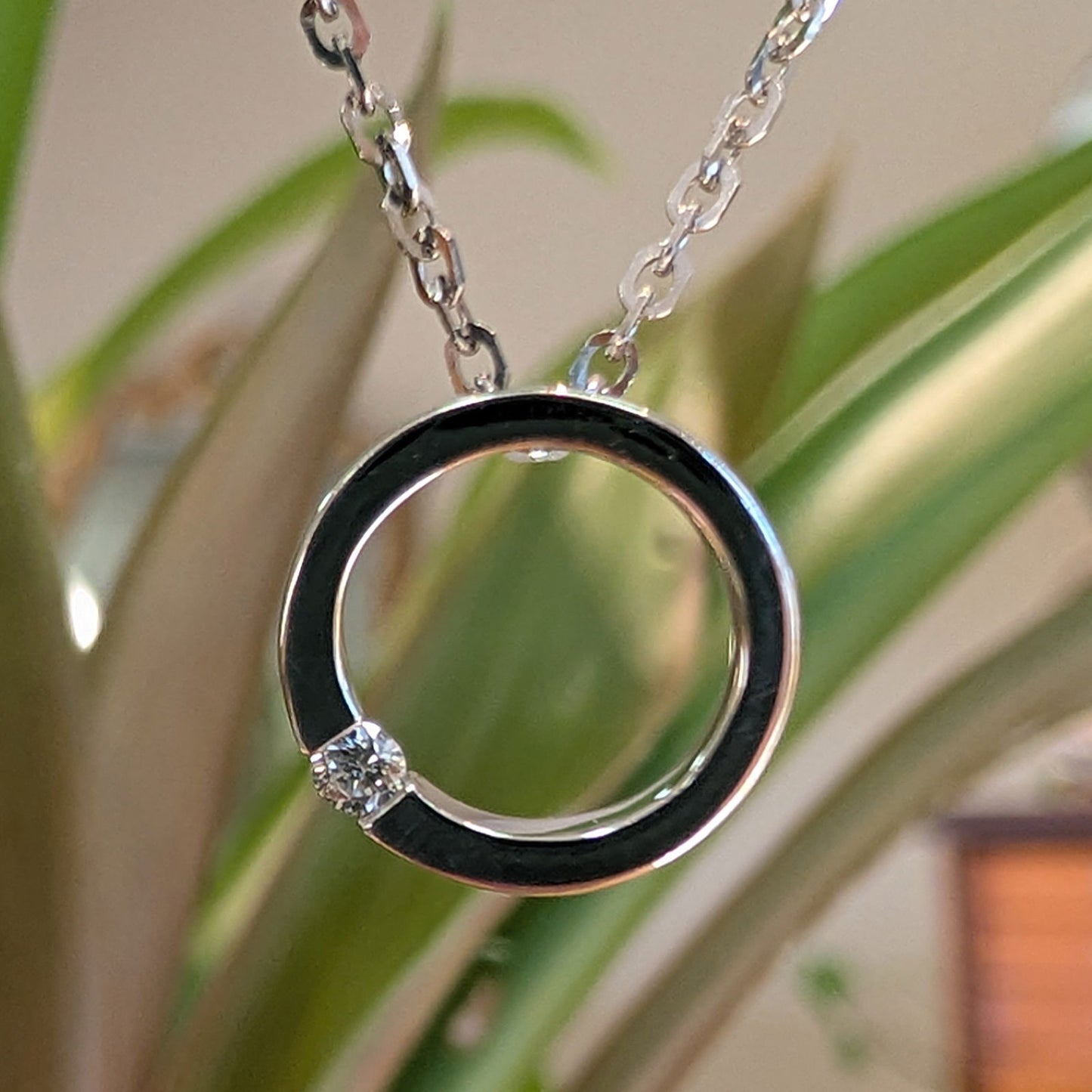 Photo of Petite Open Circle Pendant in a decorative scene, designed by , available at Plumb Gold & Plumb Silver