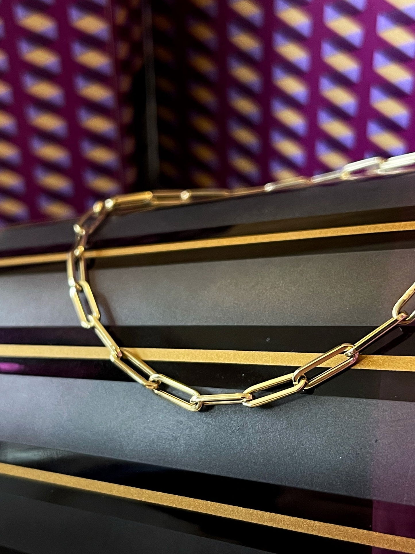 Photo of Petite Paperclip Bracelet in a decorative scene, designed by , available at Plumb Gold & Plumb Silver